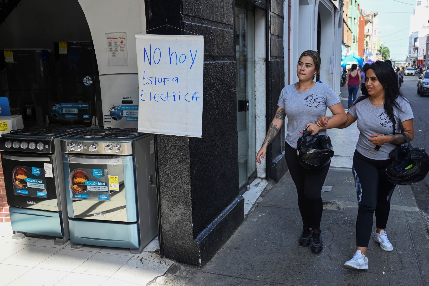 33g62qb-preview-9469-1684988417 Hai người phụ nữ đi qua tấm biển đề chữ không bán bếp điện tại cửa hàng đồ gia dụng ở Cali, Colombia, ngày 24/5. Ảnh: AFP