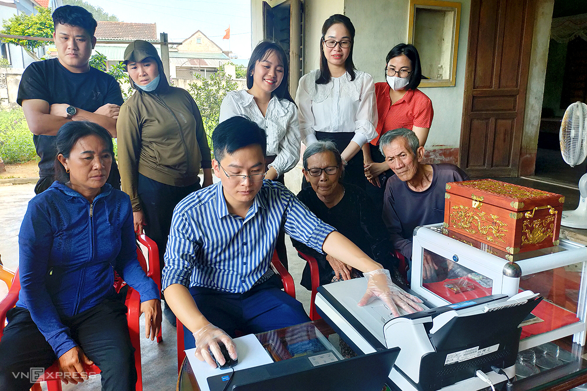 Cán bộ Trung tâm lưu trữ lịch sử tỉnh Hà Tĩnh lập bản sao sổ ghi chép trước sự chứng kiến của người thân liệt sĩ Cao Xuân Tuất. Ảnh: Xuân Liệu