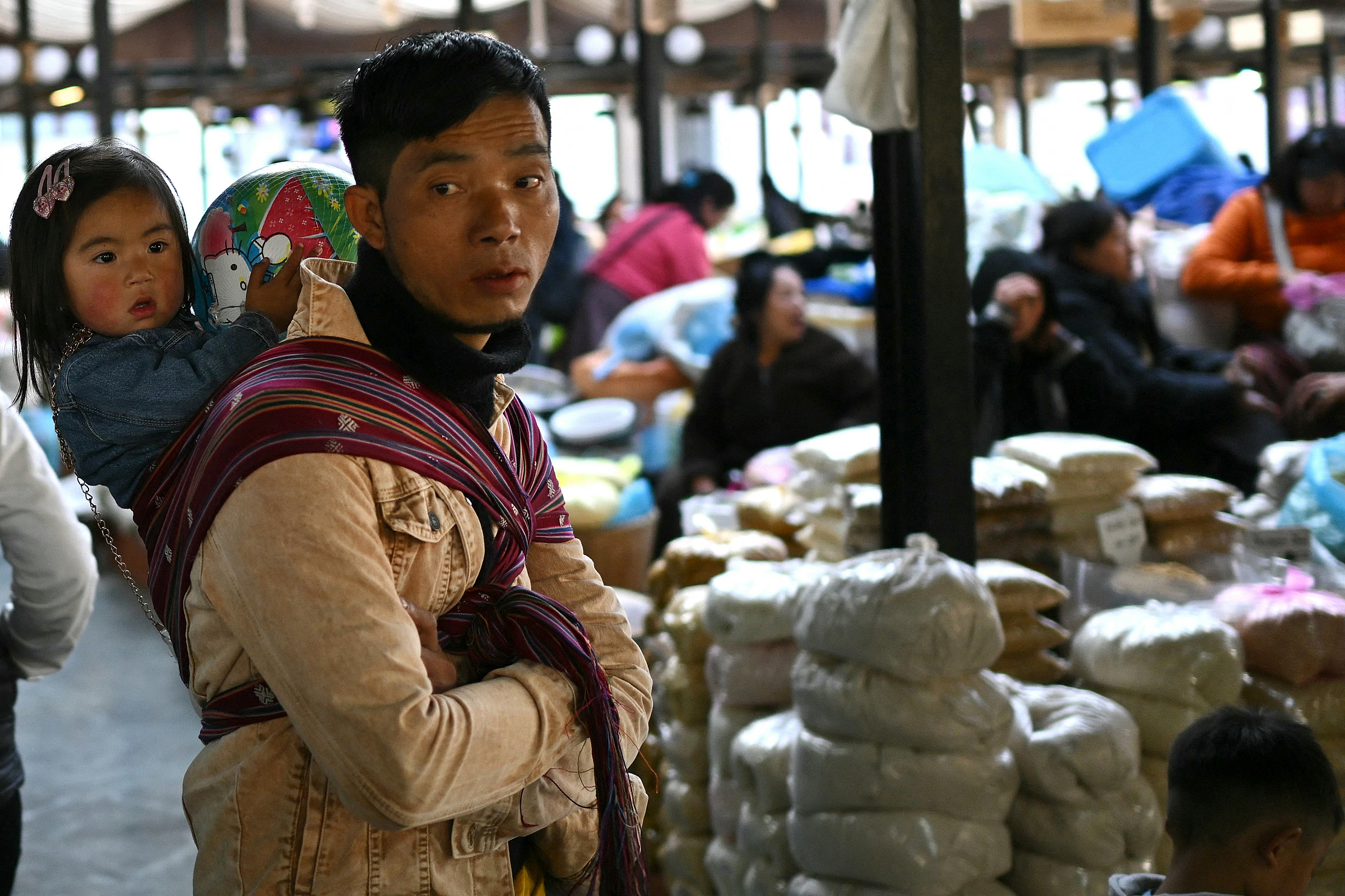 Một người đàn ông địu con bán hàng tại chợ ở Thimpu, thủ đô Bhutan, hồi tháng 1. Ảnh: AFP