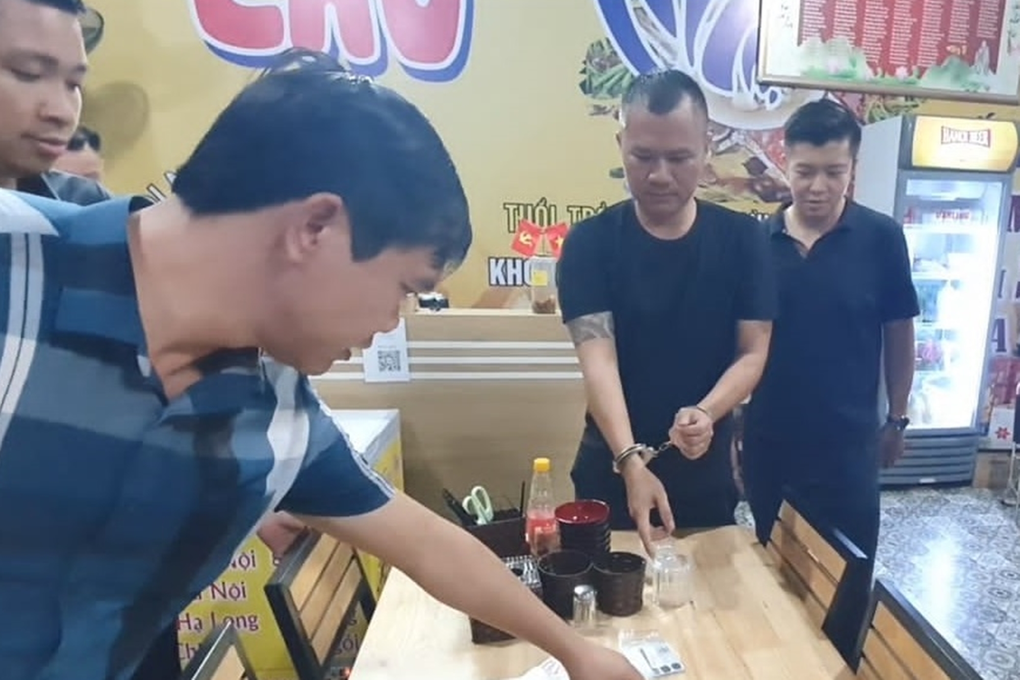 Huy (đeo còng tay) khi bị bắt. Ảnh Công an cung cấp