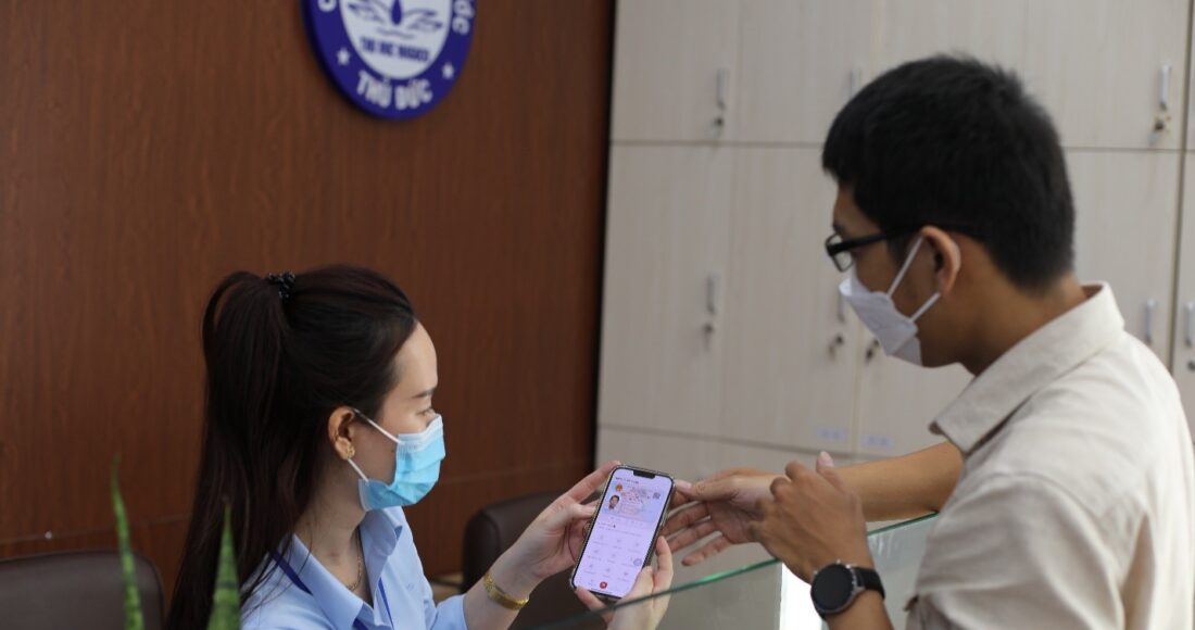 Nhân viên Công ty Cổ Phần Cấp nước Thủ Đức hướng dẫn người dân khai báo xin cấp định mức nước qua ứng dụng VneID. Ảnh: Sawaco