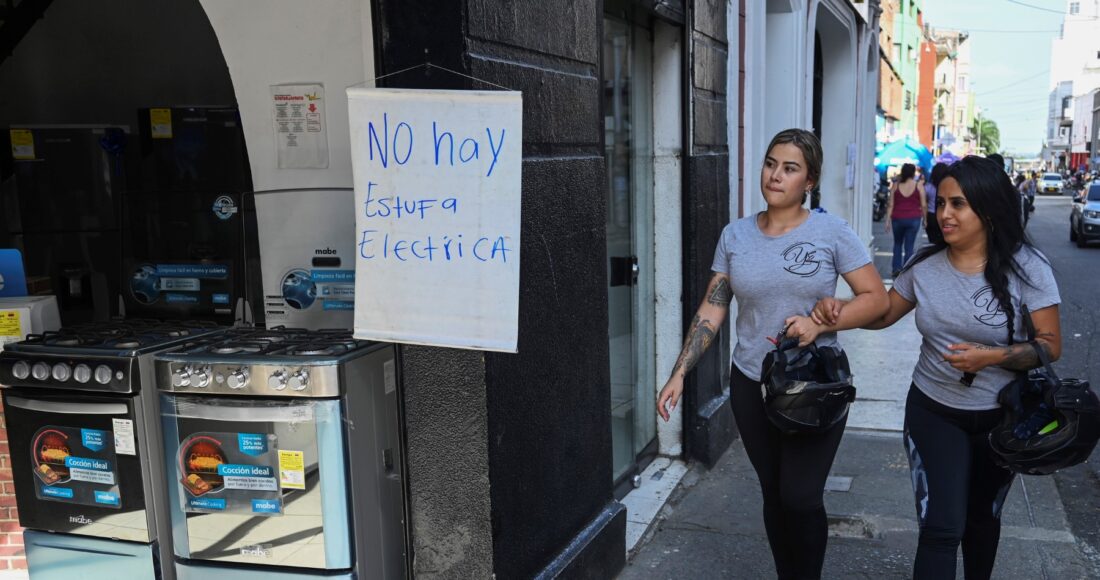 Hai người phụ nữ đi qua tấm biển đề chữ không bán bếp điện tại cửa hàng đồ gia dụng ở Cali, Colombia, ngày 24/5. Ảnh: AFP