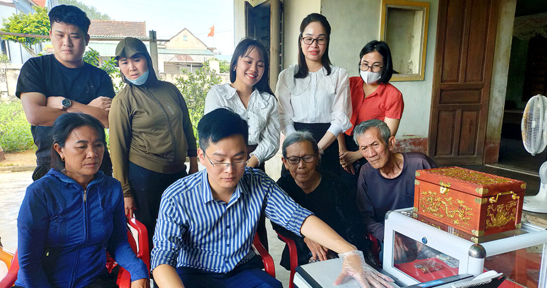Cán bộ Trung tâm lưu trữ lịch sử tỉnh Hà Tĩnh lập bản sao sổ ghi chép trước sự chứng kiến của người thân liệt sĩ Cao Xuân Tuất. Ảnh: Xuân Liệu