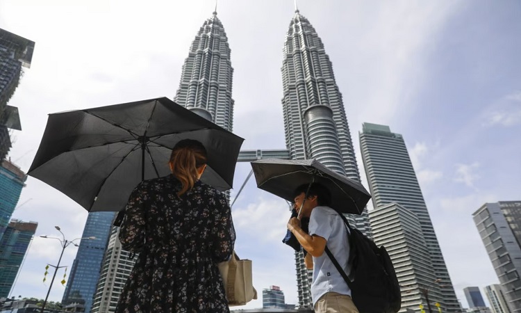 Người dân che ô khi ra đường ở Kuala Lumpur vào tháng trước. Ảnh: SCMP