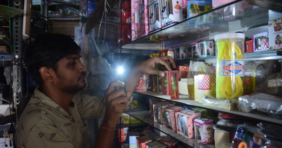 Chủ một cửa hàng ở Thane (Ấn Độ) dùng điện thoại soi đèn khi mất điện. Ảnh: Hindustan Times