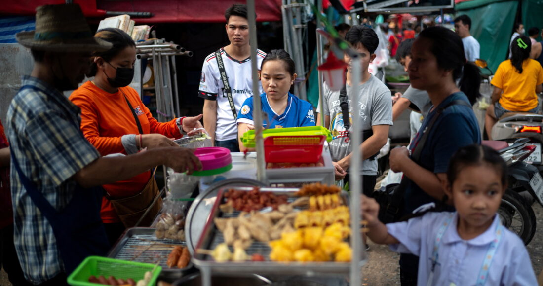 Người dân mua đồ tại một quầy hàng rong ở Bangkok (Thái Lan). Ảnh: Reuters