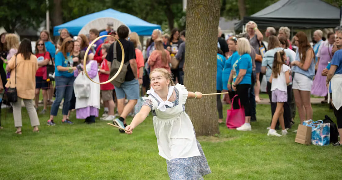 Trong khi mẹ xếp hàng xin chữ ký của Dean Butler (vai Almanzo Wlider, chồng của Laura Ingalls Wilder), Danea Jackson, 12 tuổi, đến từ Wilton (bang Iowa), chơi trò graces (trò chơi phổ biến dành cho các cô gái trẻ vào đầu những năm 1800) ở lễ hội. Một người sẽ ném chiếc vòng gỗ lên không trung để người kia bắt lấy bằng hai thanh gỗ. Người chiến thắng là người đầu tiên bắt được chiếc vòng mười lần. Ảnh: StarTribune