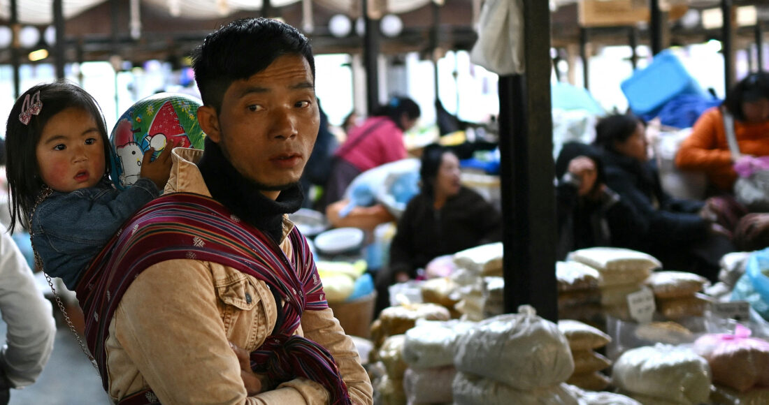 Một người đàn ông địu con bán hàng tại chợ ở Thimpu, thủ đô Bhutan, hồi tháng 1. Ảnh: AFP