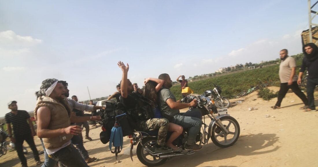 Thành viên Hamas đưa người phụ nữ Israel (ngồi giữa) bị bắt làm con tin từ khu định cư Kfar Azza của Israel tới Dải Gaza hôm 7/10. Ảnh: AP