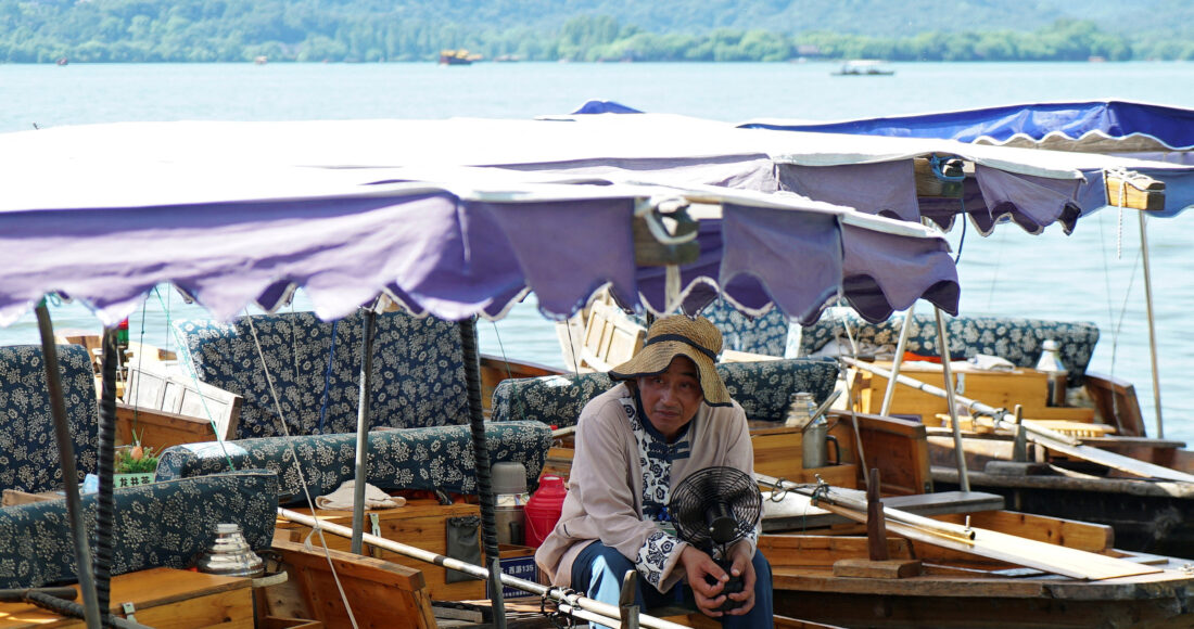 Người chèo thuyền cầm quạt tích điện tại Hàng Châu ngày 2/8. Ảnh: Reuters