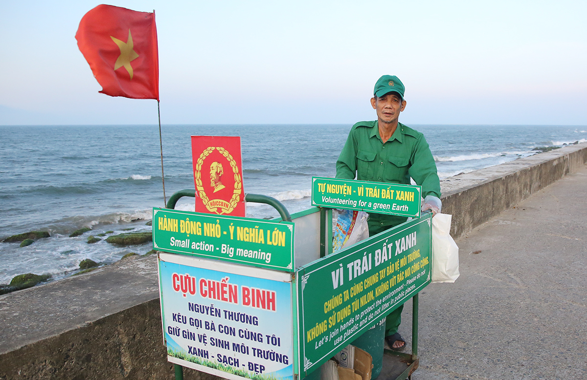 Ông Nguyễn Thương đẩy xe đi dọc bờ kè biển Cửa Đại nhặt rác. Ảnh: Đắc Thành