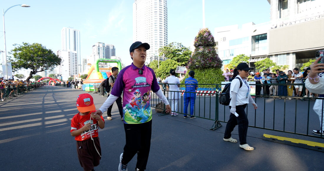 Trường Giang nắm tay một runner 6 tuổi cùng về đích. Ảnh: VM