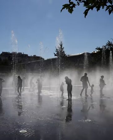 Người dân giải nhiệt bên dưới đài phun nước ở công viên Madrid Rio tại Madrid hôm 23/7. Ảnh: AFP