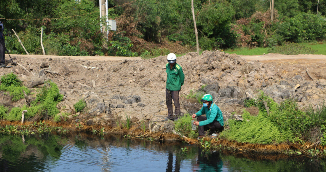 Lực lượng chức năng lấy mẫu nước dưới dòng kênh bị ô nhiễm do nhà máy phân bón công ty xả thải hồi tháng 6. Ảnh: Nam An