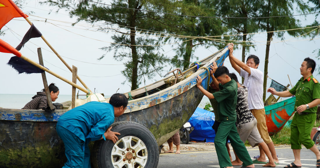 Ngư dân và lực lượng chức năng Sầm Sơn kéo thuyền vào bãi tập kết chiều 6/9. Ảnh: Lê Hoàng