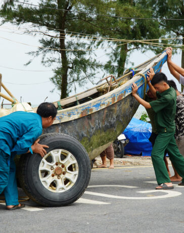 Ngư dân và lực lượng chức năng Sầm Sơn kéo thuyền vào bãi tập kết chiều 6/9. Ảnh: Lê Hoàng