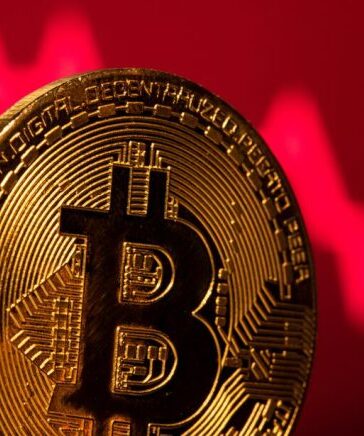 Một biểu trưng của Bitcoin được đặt trước hình minh họa thị trường giảm giá. Ảnh: Reuters