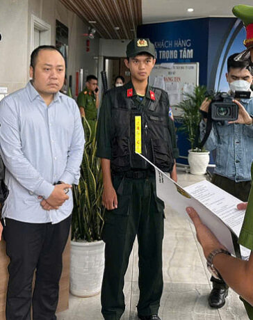 Nguyễn Quang Hoàng nghe đọc lệnh khám xét nơi ở, ngày 8/11. Ảnh: Công an cung cấp