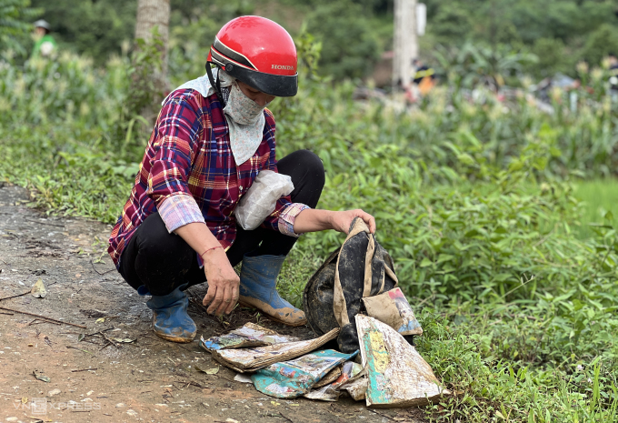 Người thân bên cặp sách còn sót lại của học trò Làng Nủ sau trận lũ quét rạng sáng 10/9. Ảnh: Hoàng Phương