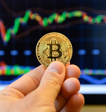 Nhà đầu tư đang cầm biểu trưng Bitcoin trước màn hình theo dõi thị giá. Ảnh: CNBC