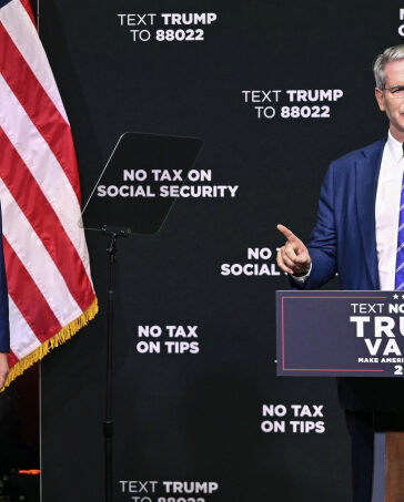 Ông Donald Trump (trái) lắng nghe Scott Bessent phát biểu về kinh tế tại sự kiện ở Asheville, bang Bắc Carolina ngày 14/8. Ảnh: AP