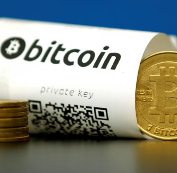 Biểu trưng của Bitcoin đặt cạnh một biên lai có chứa mã QR truy cập vào ví lưu trữ. Ảnh: Reuters