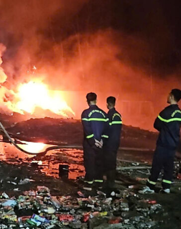 Cảnh sát túc trực dập ngọn lửa âm ỉ dưới đống tàn tro bên trong nhà xưởng, tối 1/12. Ảnh: Hùng Lê